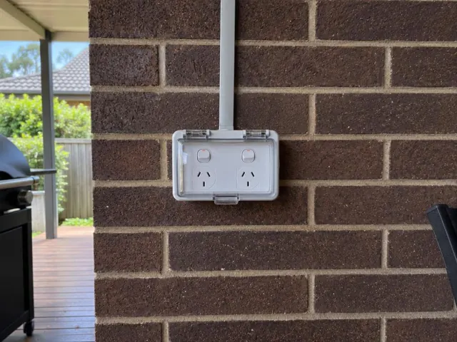 Outdoor double power point on a brick exterior wall with conduit near a covered patio in Killarney Vale